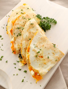 Delicious pumpkin quesadilla sliced and ready to serve with chopped parsley.